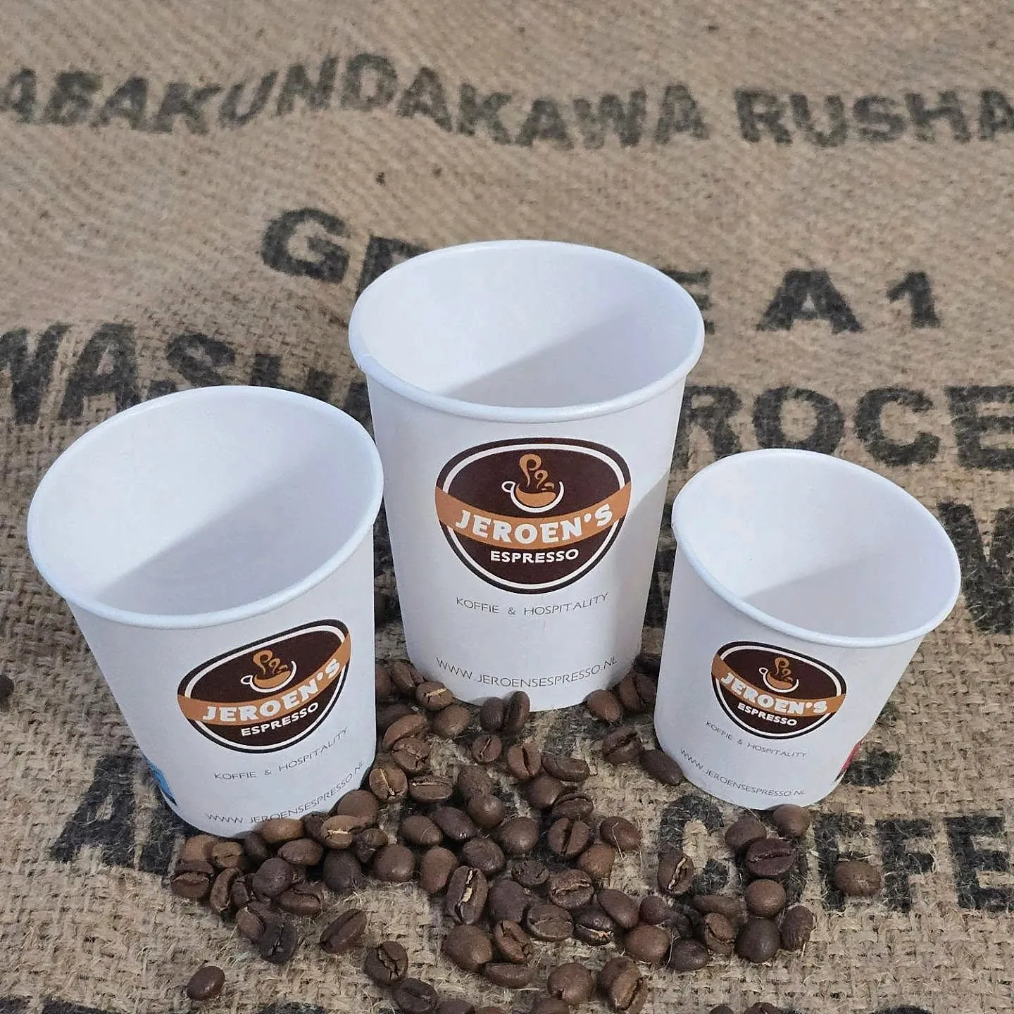 Drie bedrukte bekers van Jeroen’s Espresso tussen de koffiebonen