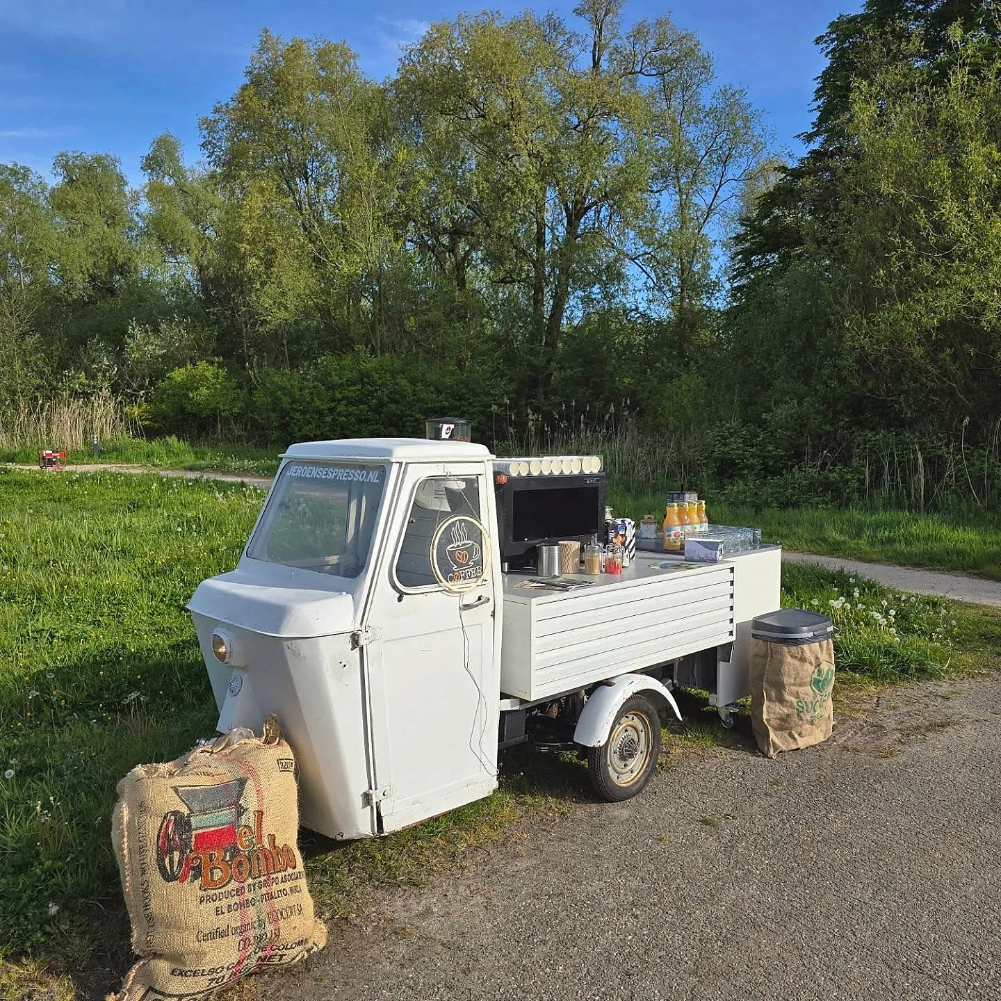De mobiele koffietuktuk op een groene buitenlocatie